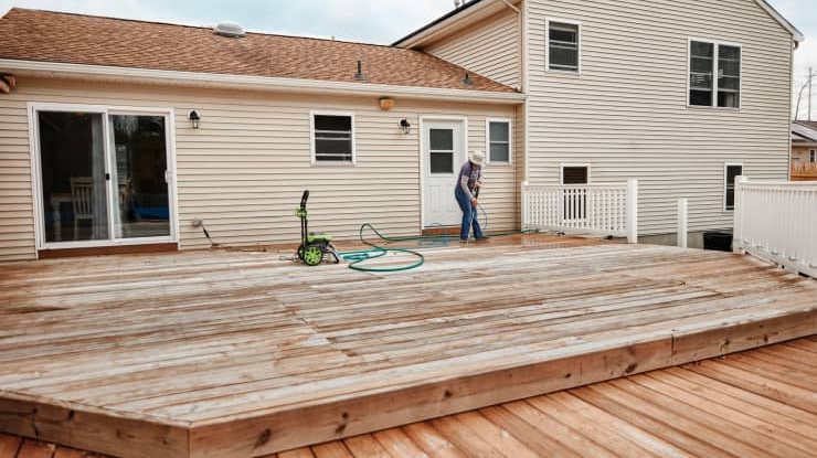 Person cleaning a wooden deck